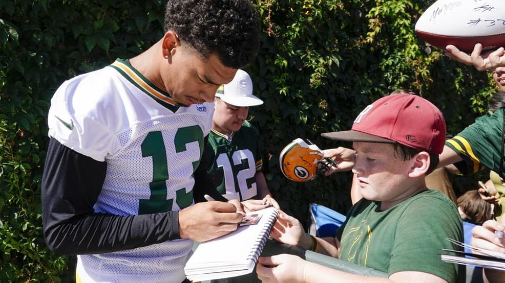 Allen Lazard signing a card for a fan